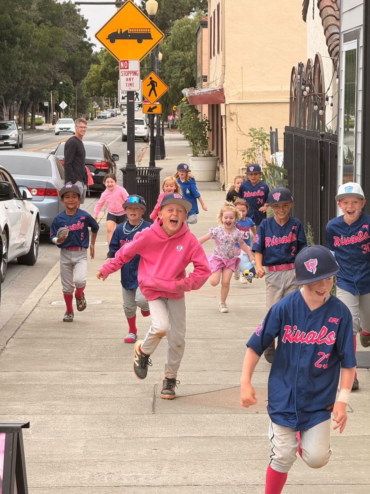 Rivals players in navy jerseys sprinting down a sidewalk, laughing